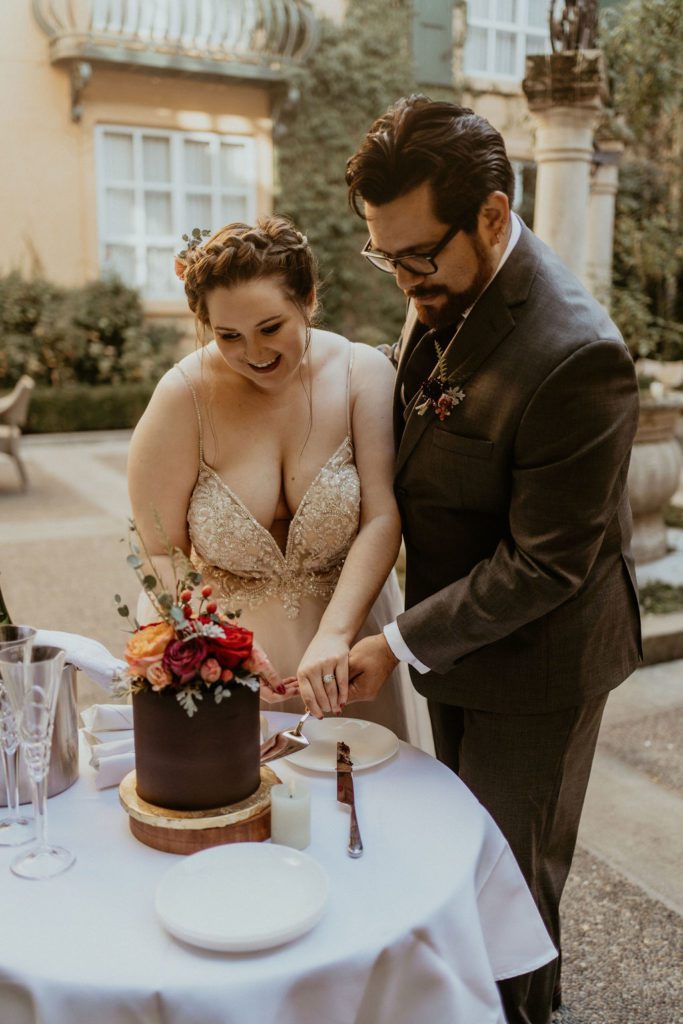 Couple cutting their cake after their elopement Ceremony in their French Inspired courtyard Elopement. French Elopement and destination elopement photography
