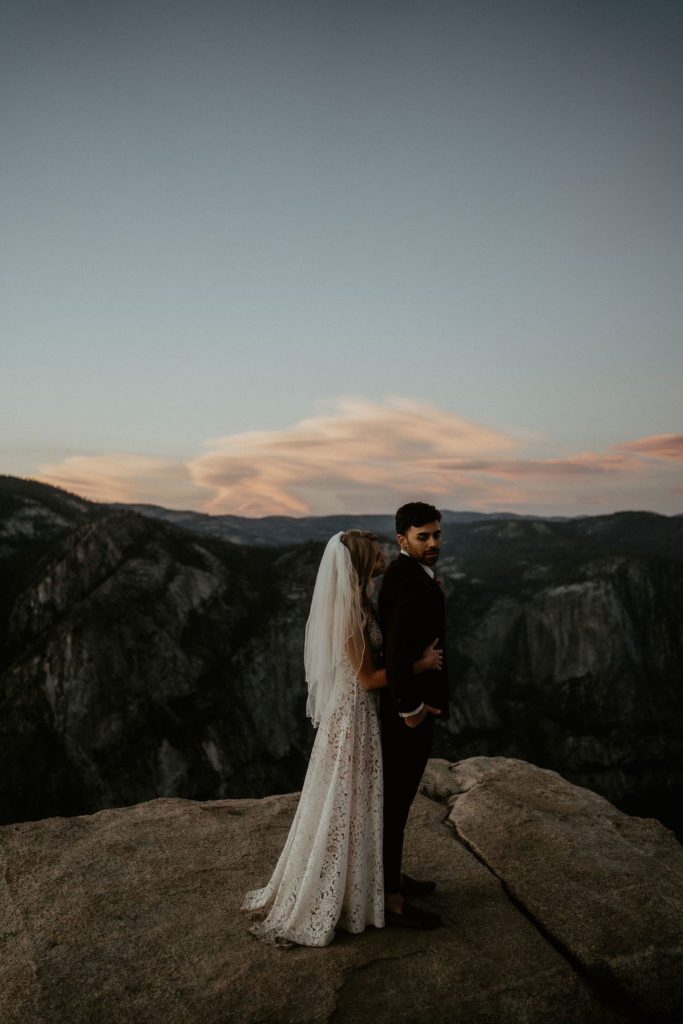Eloping couple cuddled together on a cliff at Taft Point in Yosemite National Park California Elopement Photography