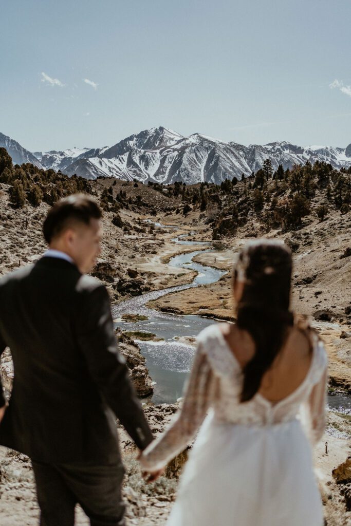 eloping couple looking out at the view, Mammoth Lakes and a beautiful hot creek and snowy mountians during their elopement