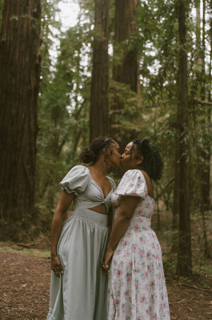 Couple kissing in Front of the redwoods facing eachother 