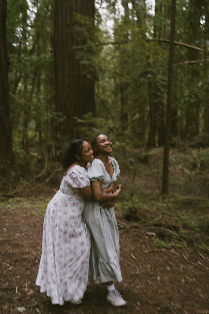 Couple cuddling and walking slowly past the camera while laughing during their engagement photos in the Northern California Redwoods