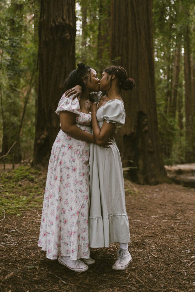 Couple kissing in front of two giant Redwood trees during their engagement session in Northern California 