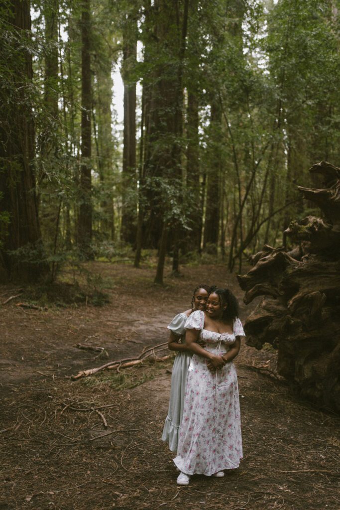 Lesbian Couple cuddling in the redwoods during their engagement photos Candid moments during engagement session